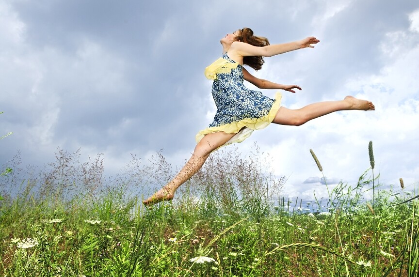 Woman in sundress leaping in weeds