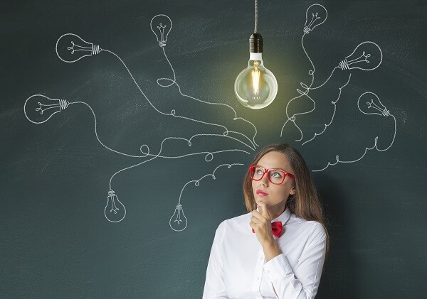 Woman in red glasses looking at hanging lightbulb