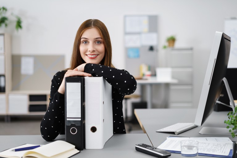 Business woman leaning on binders at desk