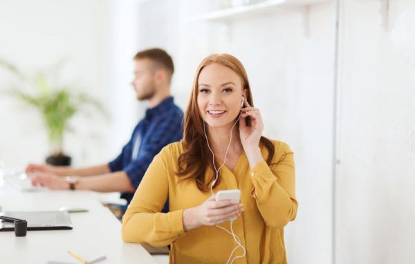 woman with earphones and smartphone at office