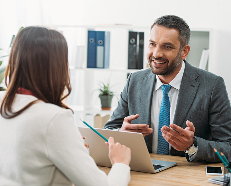 Man in Suit Talking to Woman at Desk