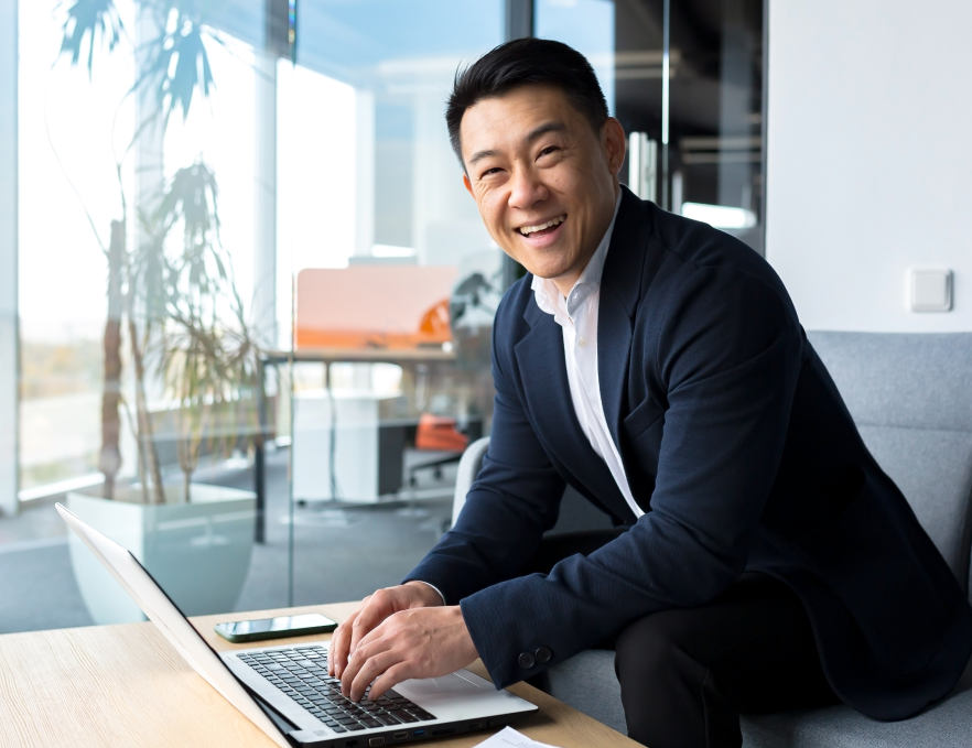 Smiling Asian Man Working on Laptop
